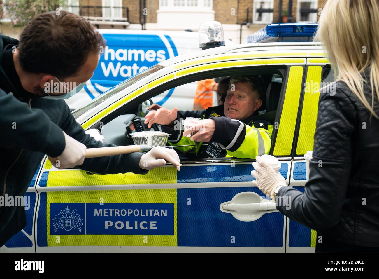 Food and drink is passed into a police car, at a free drive-through for the emergency services at The Berkeley Hotel as the UK continues in lockdown to help curb the spread of the coronavirus. Stock Photo
