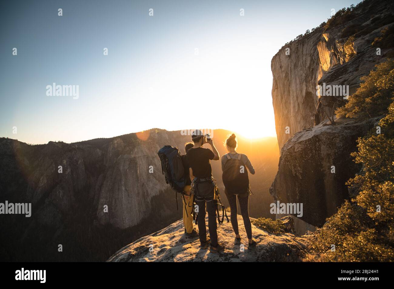 A group of people standing on a rock photographing a sunset. Stock Photo