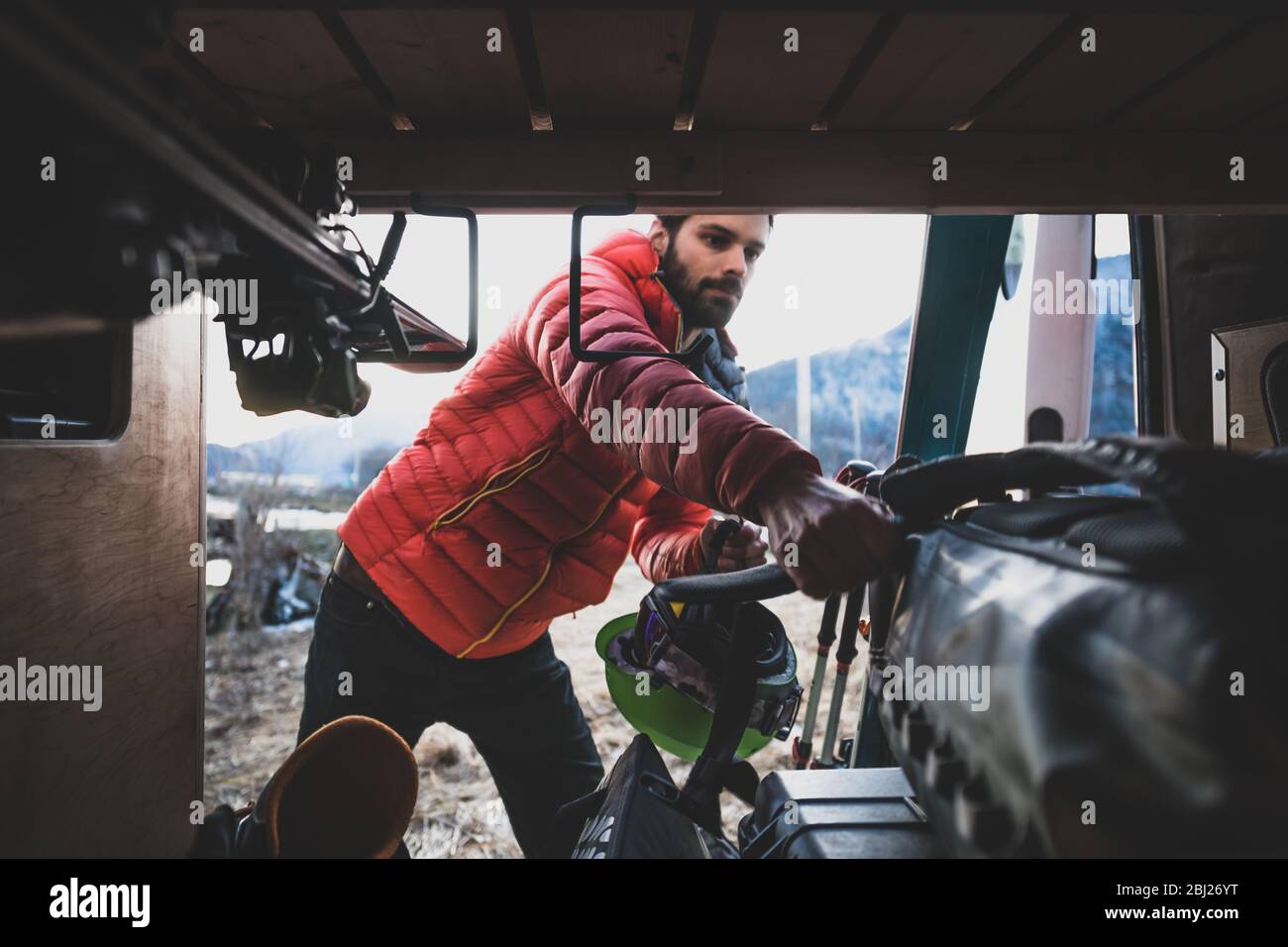 Man reaching into a van to take out skiing equipment. Stock Photo