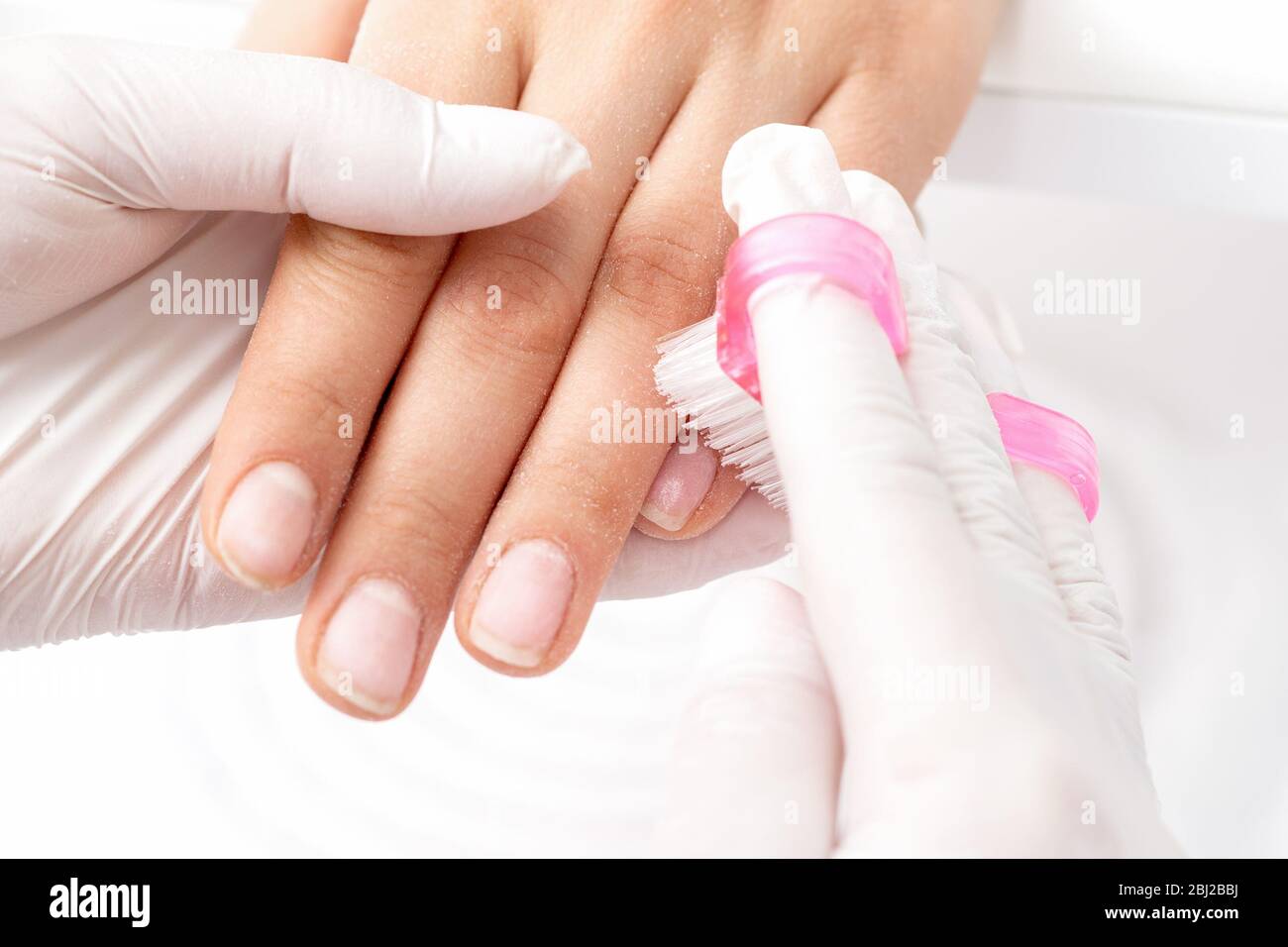 Closeup of manicurist hands is removing dust from nails with a brush
