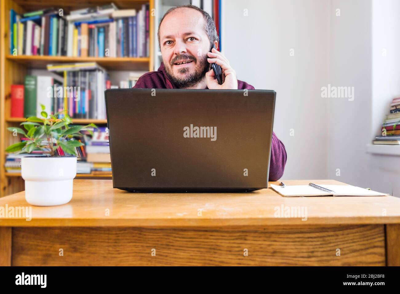 Man working from home office. Adult bearded man concentrated, working online from home on computer laptop behind vintage desk Stock Photo