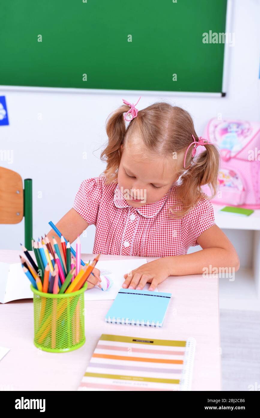 Little girl drawing at the desk in classroom Stock Photo - Alamy