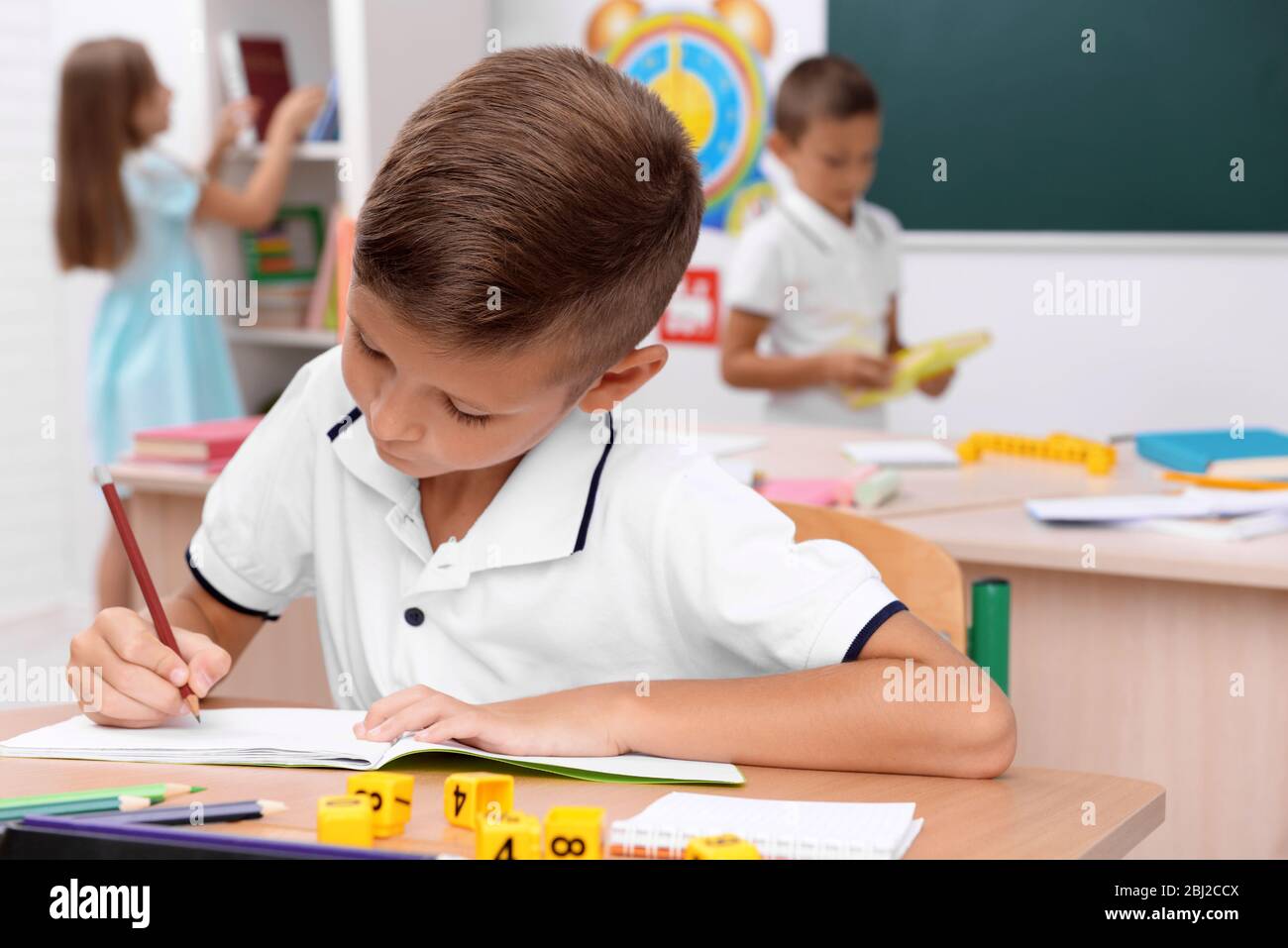 Little boy drawing at the desk in classroom Stock Photo - Alamy