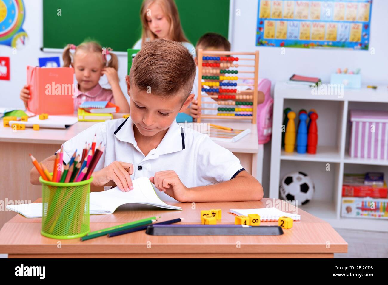 Little boy drawing at the desk in classroom Stock Photo - Alamy