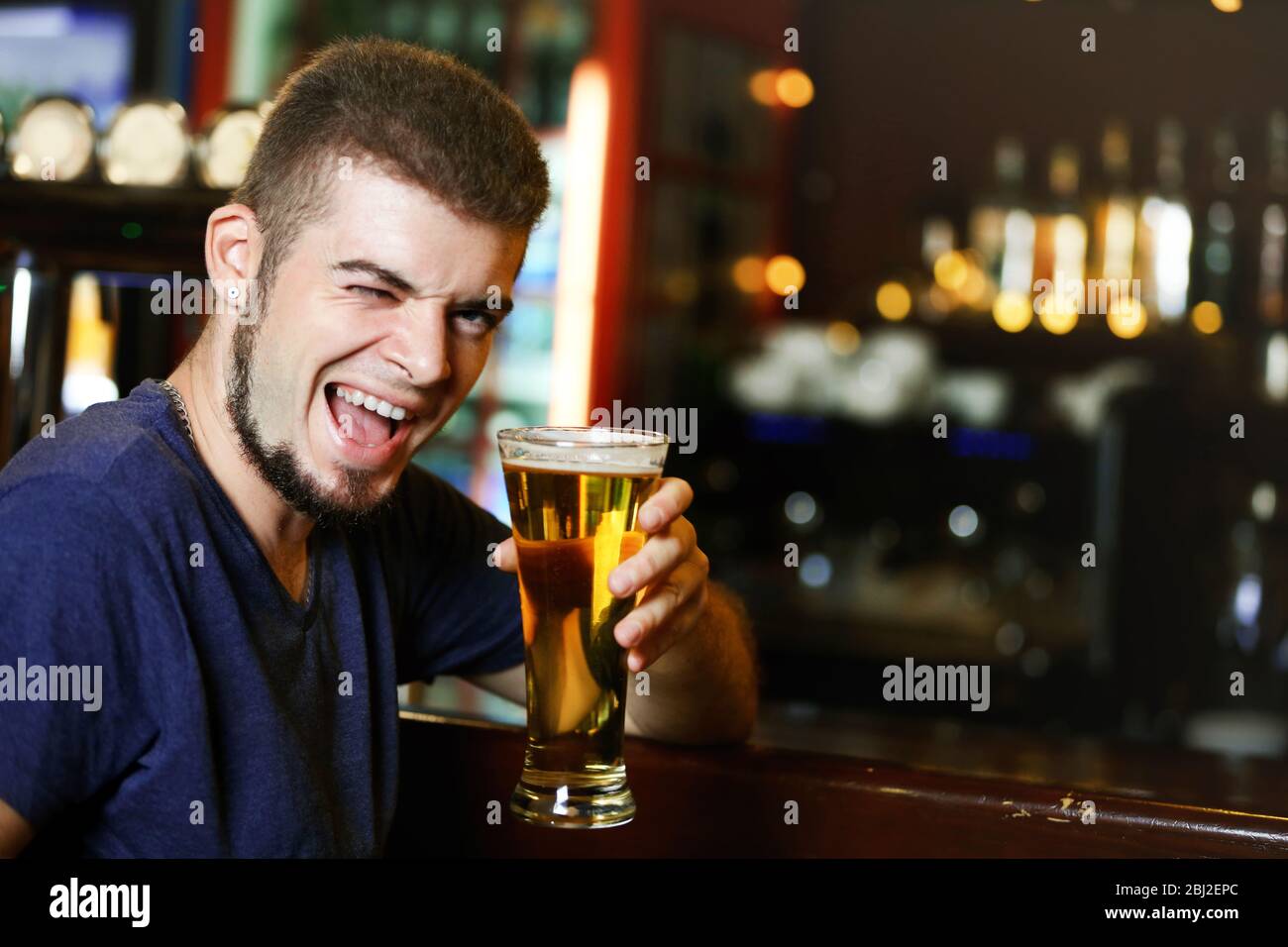 Young man drinking beer in bar Stock Photo - Alamy