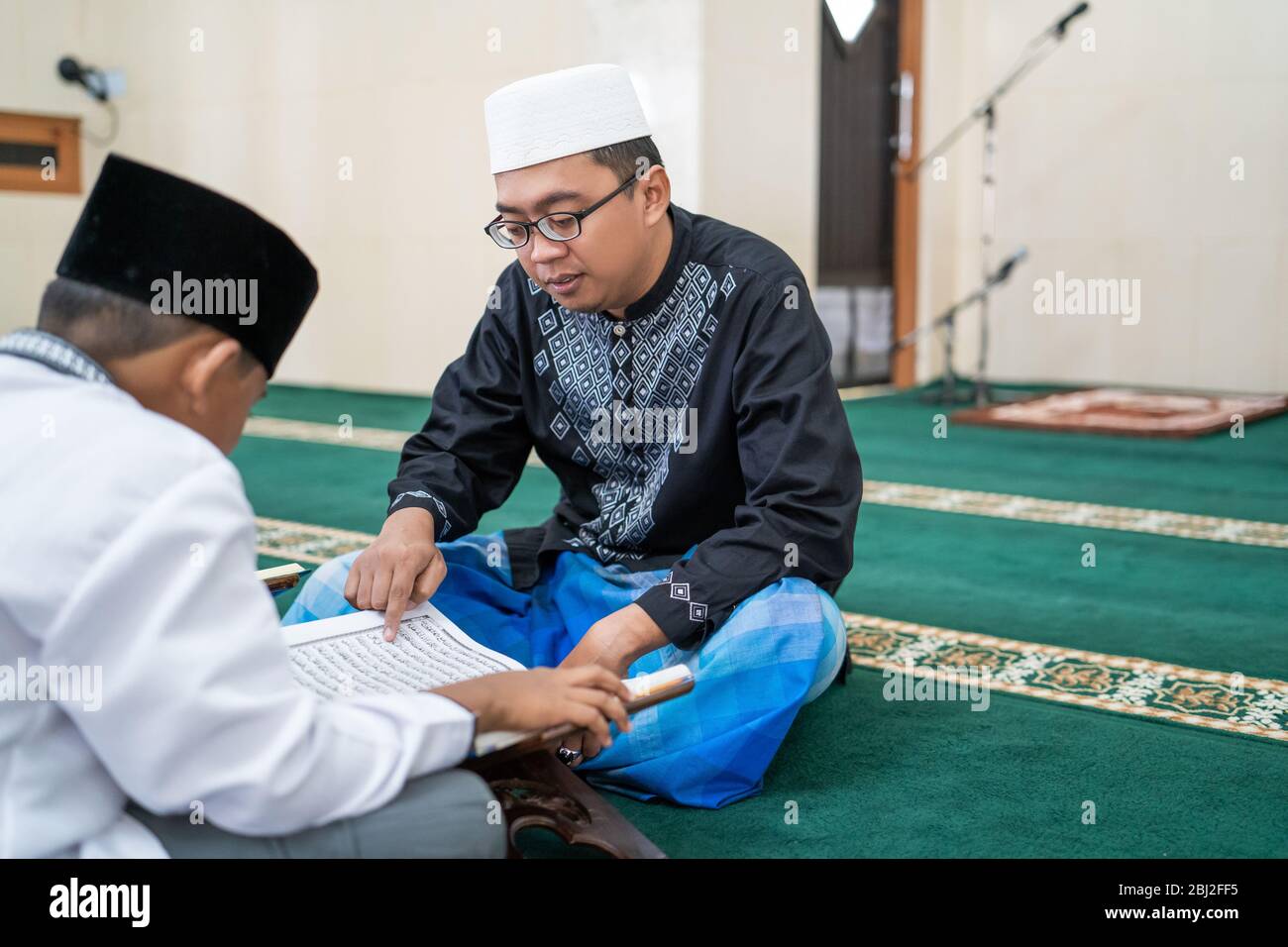 teacher is teaching muslim kid how to read holy quran in the mosque Stock Photo