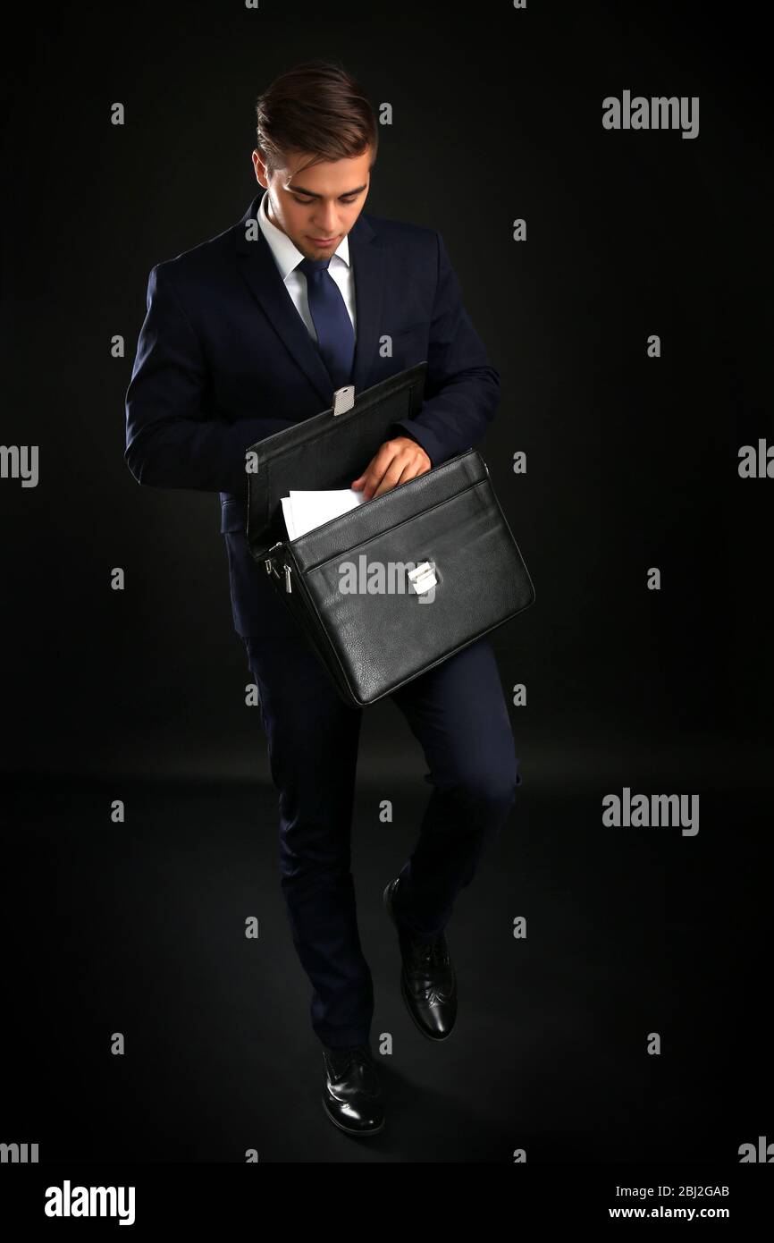 Elegant man in suit with briefcase on dark background Stock Photo - Alamy