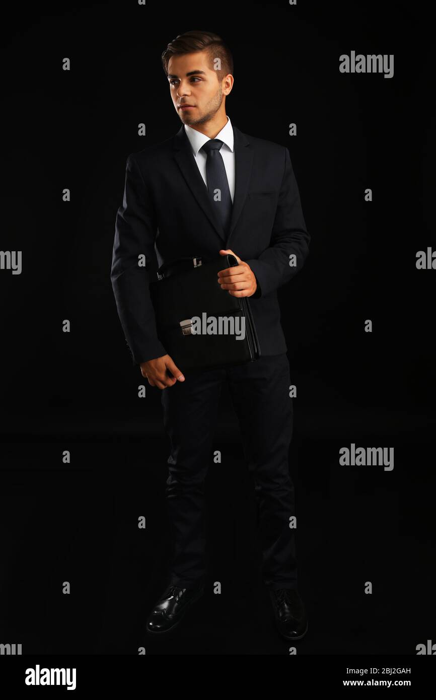 Elegant man in suit with briefcase on dark background Stock Photo - Alamy