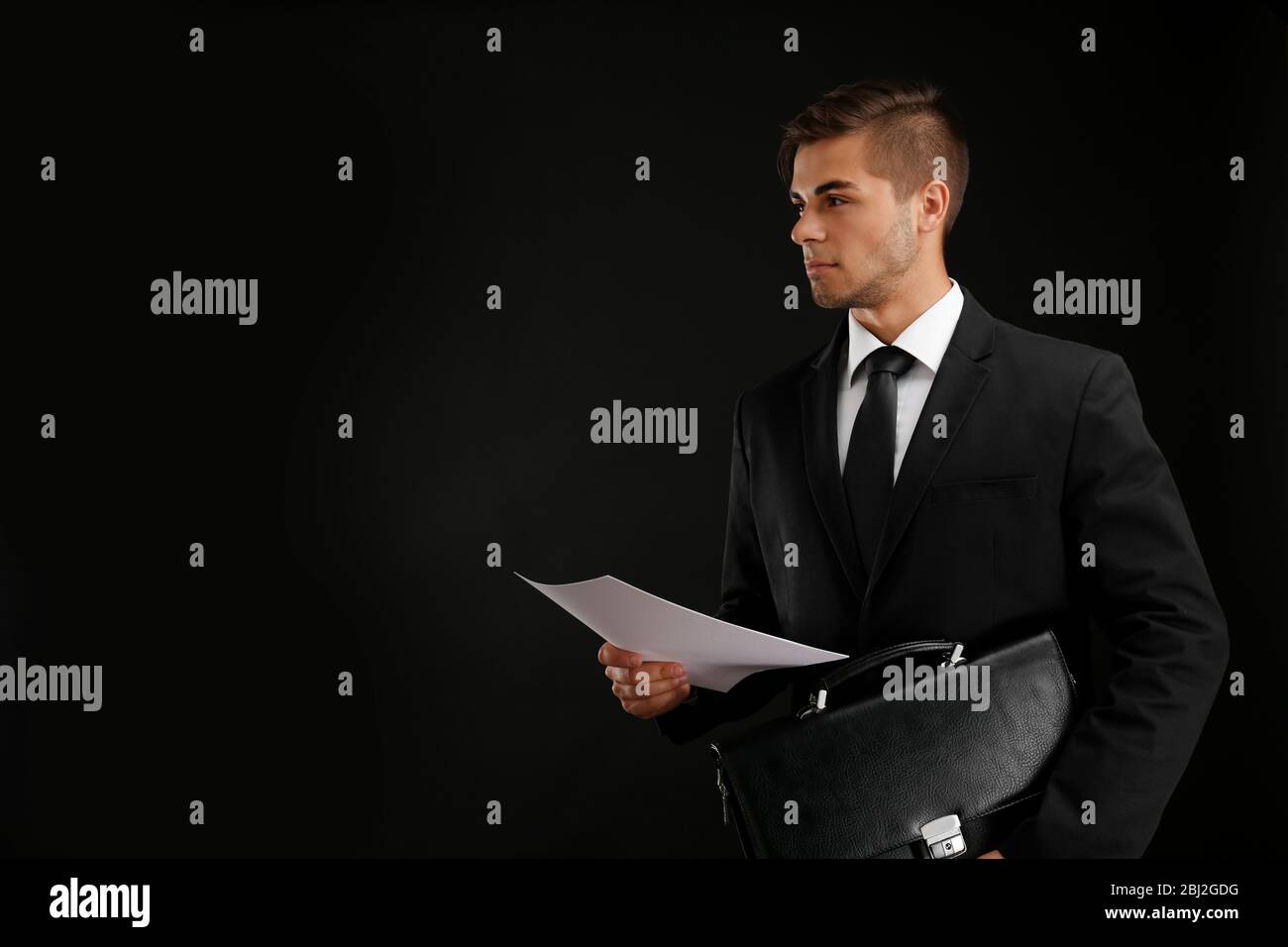 Elegant man in suit with briefcase on dark background Stock Photo - Alamy