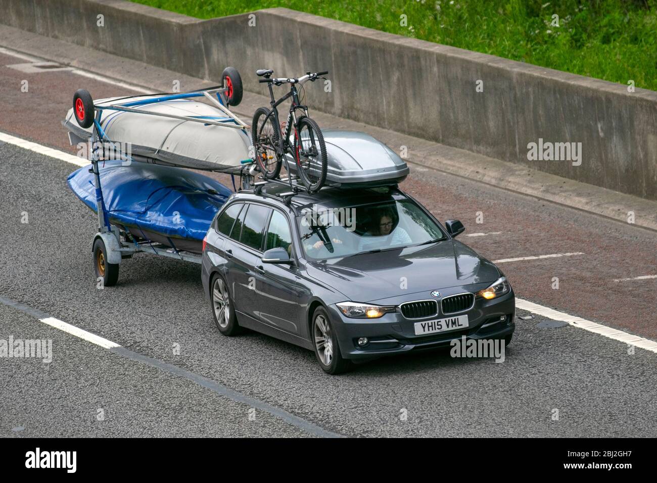 2015 BMW 320D Xdrive Sport Auto with roof box and cycle rack; Towing canoe trailer. Vehicular traffic moving vehicles, driving vehicle on UK roads, motors, motoring on the M6 motorway highway Stock Photo