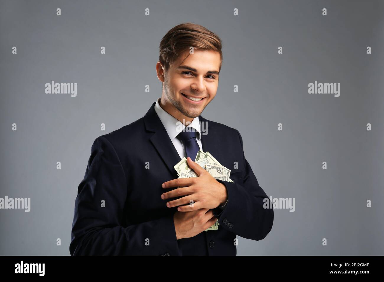 Elegant man in suit holding money on gray background Stock Photo - Alamy