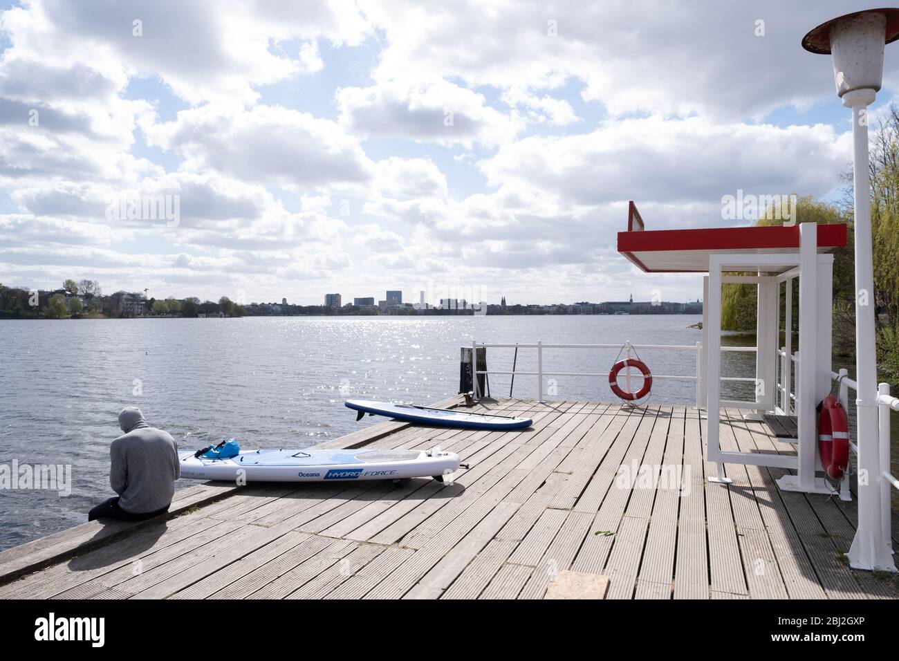 14.04.2020, Hamburg, Alster, Stand-up-Paddler sitzt neben seinem Supboard am Anleger Stock Photo