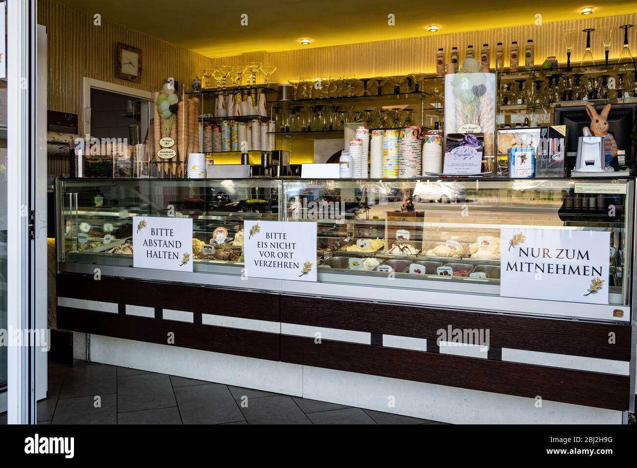 Ein Eisladen verkauft Eis zum Mitnehmen, es darf nicht vor Ort verzehrt werden. Schilder mit Hinweisen zum Abstandshalten am Tresen Stock Photo