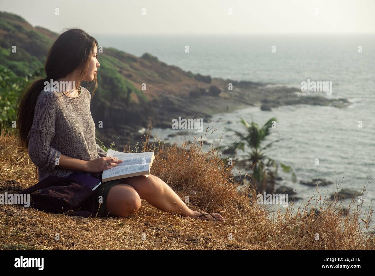 Young Woman Reading Book While Sitting Outdoors, close-up view Stock Photo