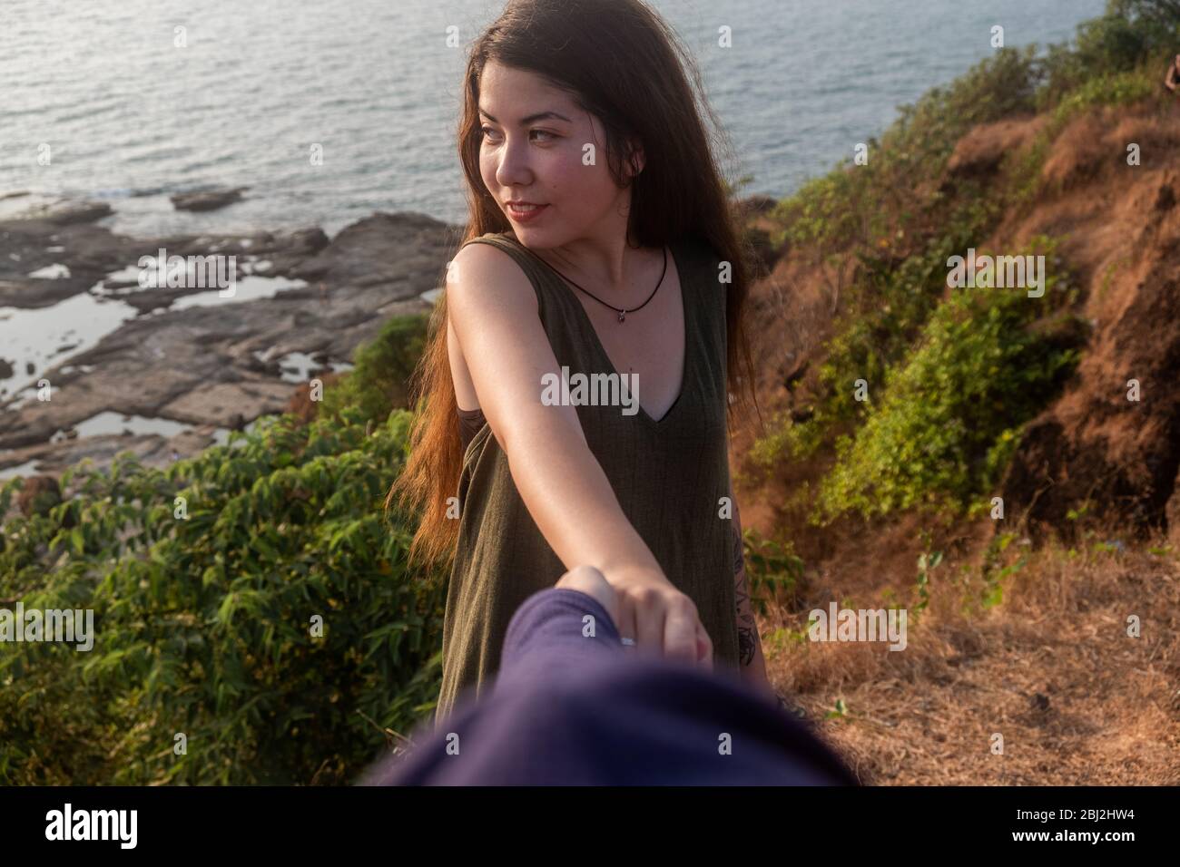 Shot of a young woman leading someone by the hand at the beach Stock Photo