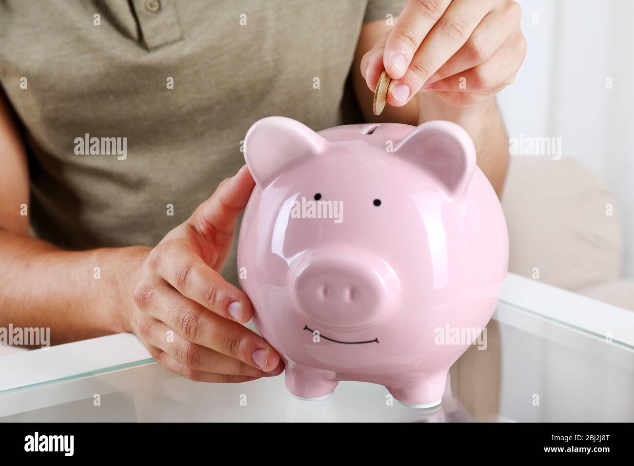 Man put coin into a piggy-bank Stock Photo - Alamy