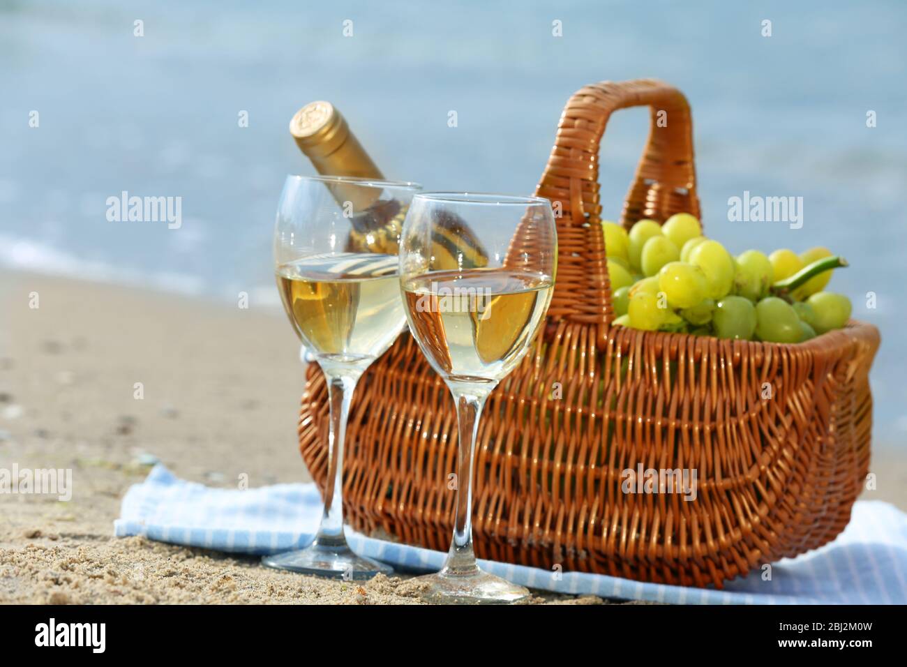 Picnic basket with bottle of wine on sand beach Stock Photo - Alamy