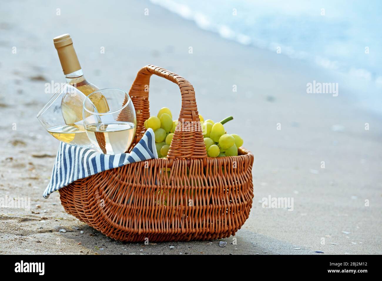 Picnic basket with bottle of wine on sand beach Stock Photo - Alamy
