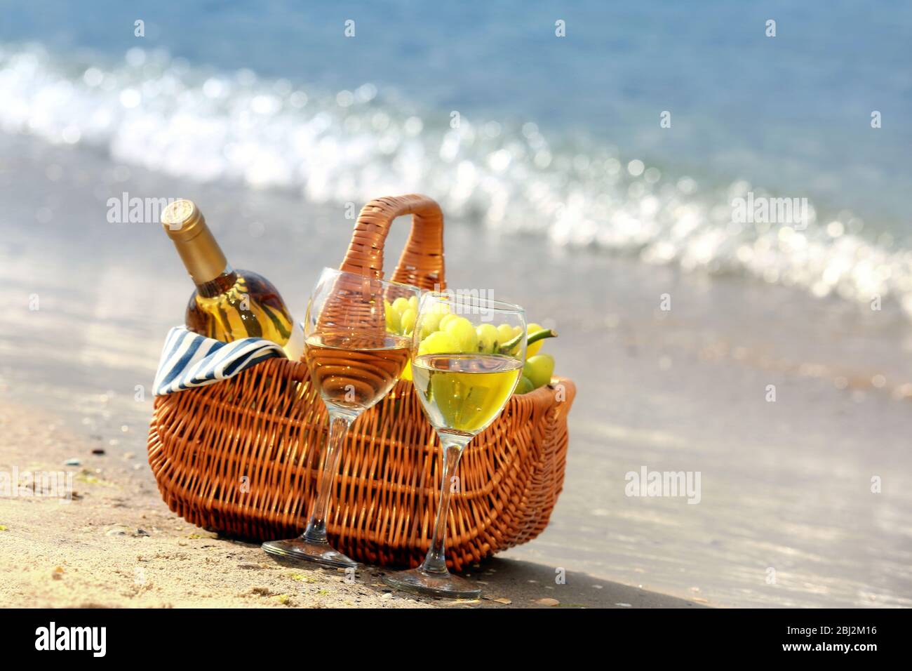 Picnic basket with bottle of wine on sand beach Stock Photo - Alamy
