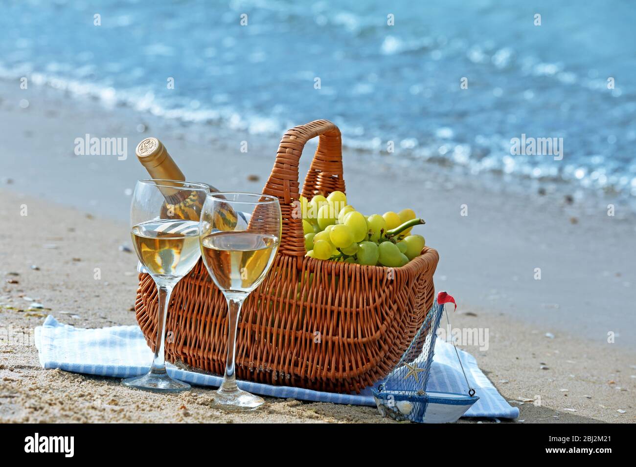 Picnic basket with bottle of wine on sand beach Stock Photo - Alamy