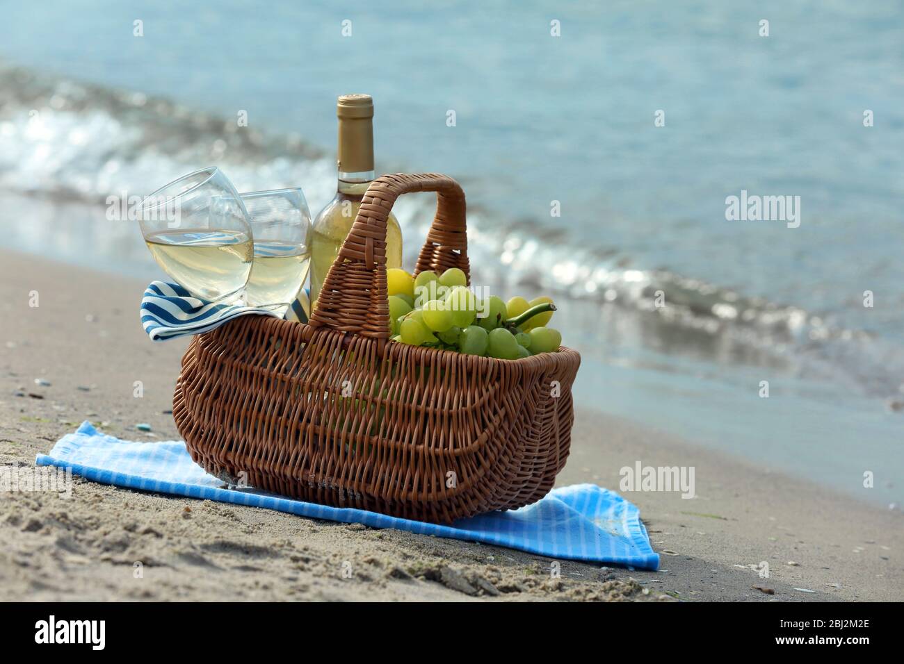 Picnic basket with bottle of wine on sand beach Stock Photo - Alamy