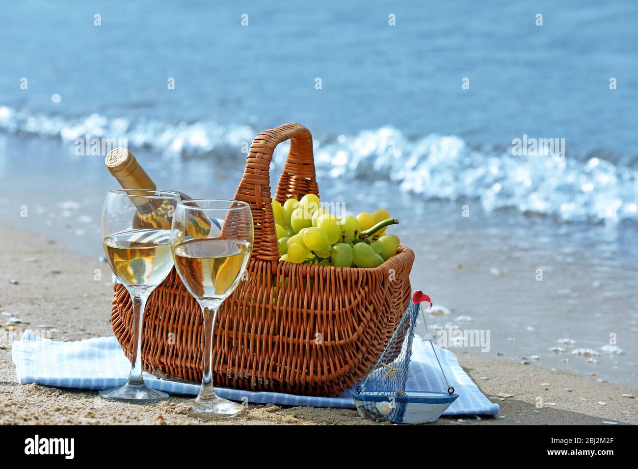 Picnic basket with bottle of wine on sand beach Stock Photo - Alamy