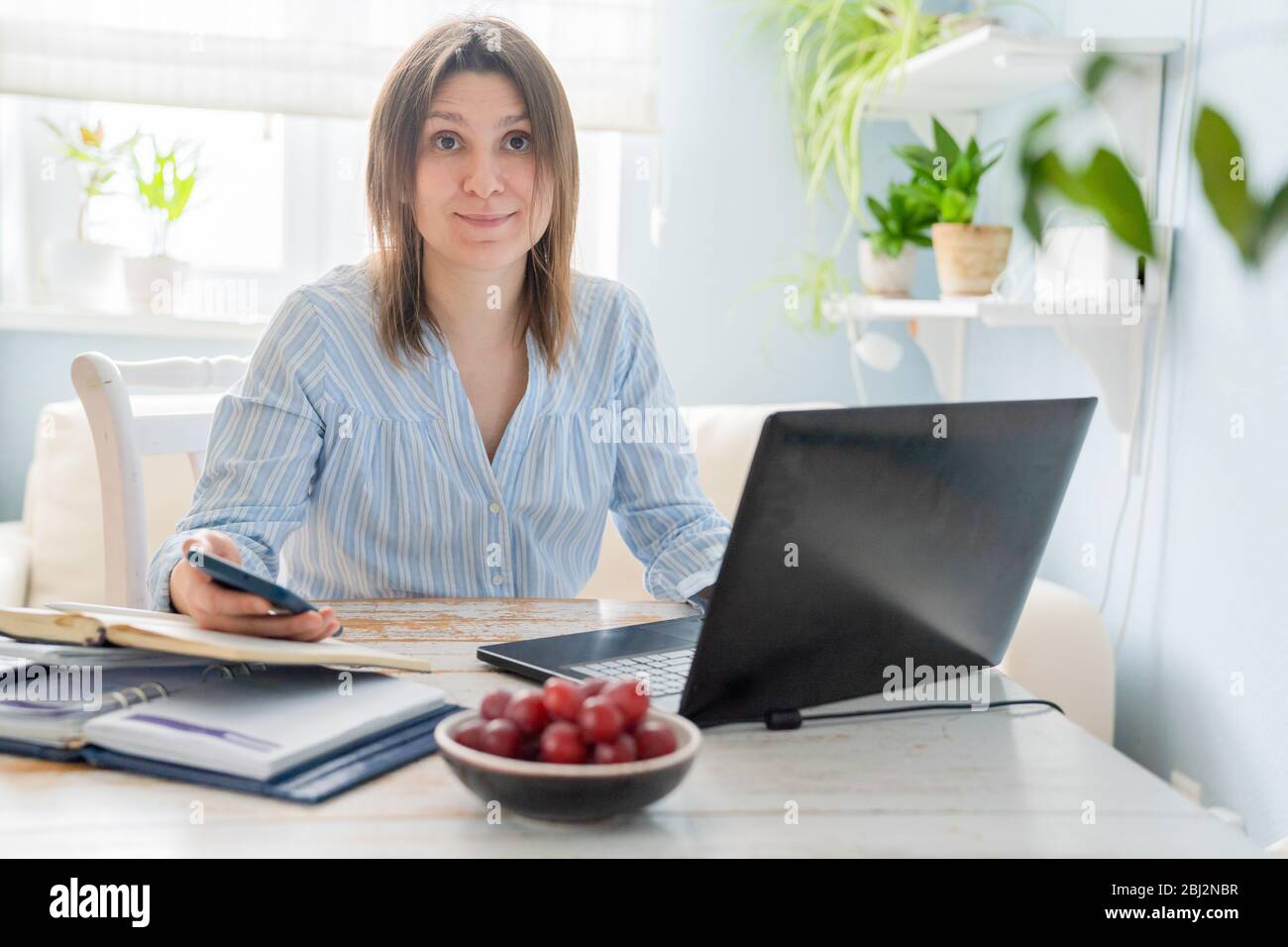 Female working from home with computer, books, phone Stock Photo