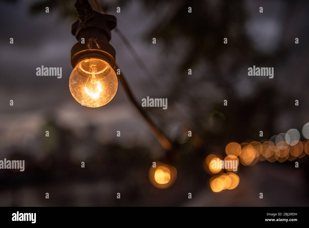 A line of  incandescent lamps in the street and bokeh. Stock Photo