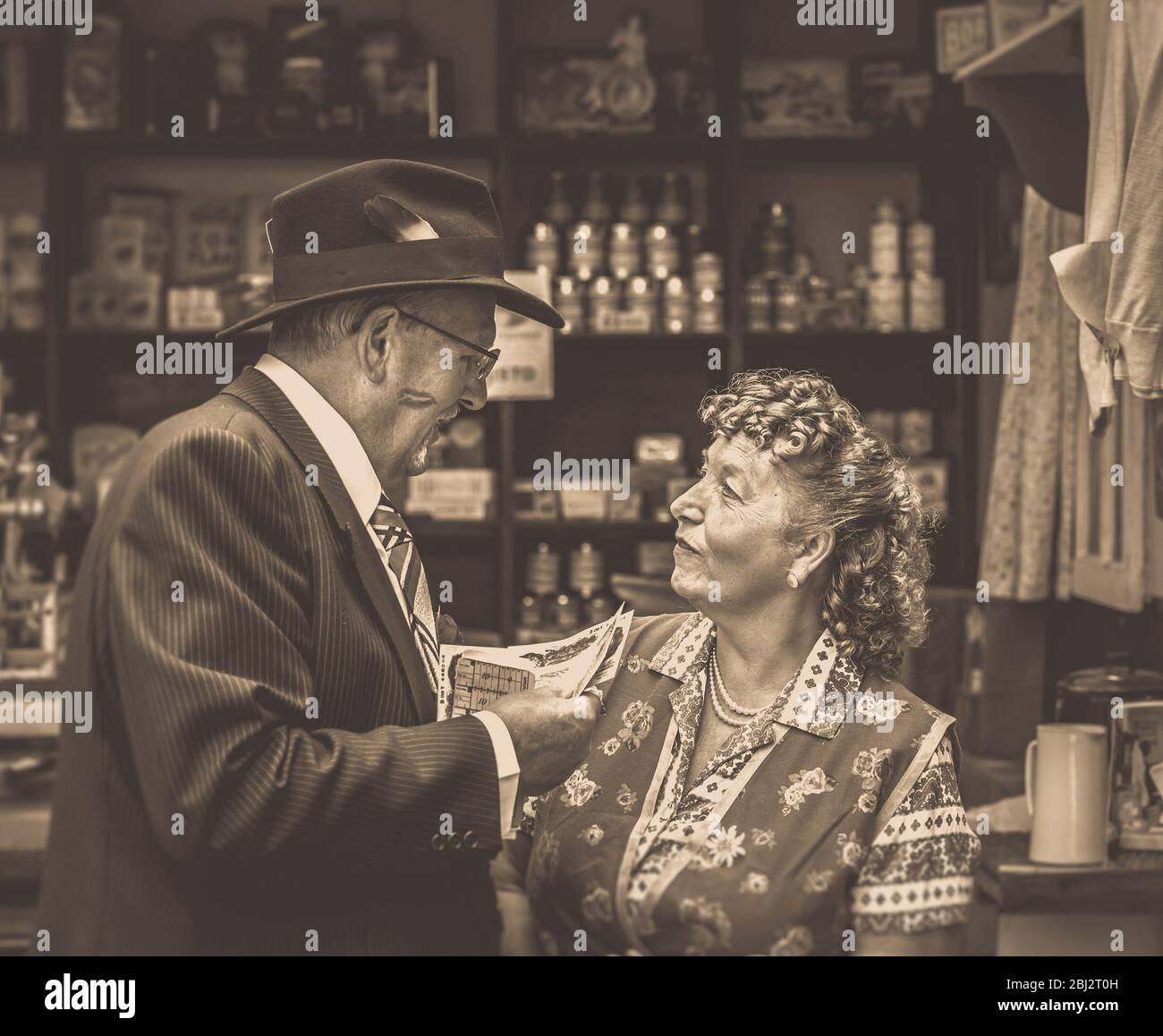 Sepia photo of 1940s spiv doing a deal with shopkeeper in WW2 grocery shop, 1940s WWII summer event. Stock Photo