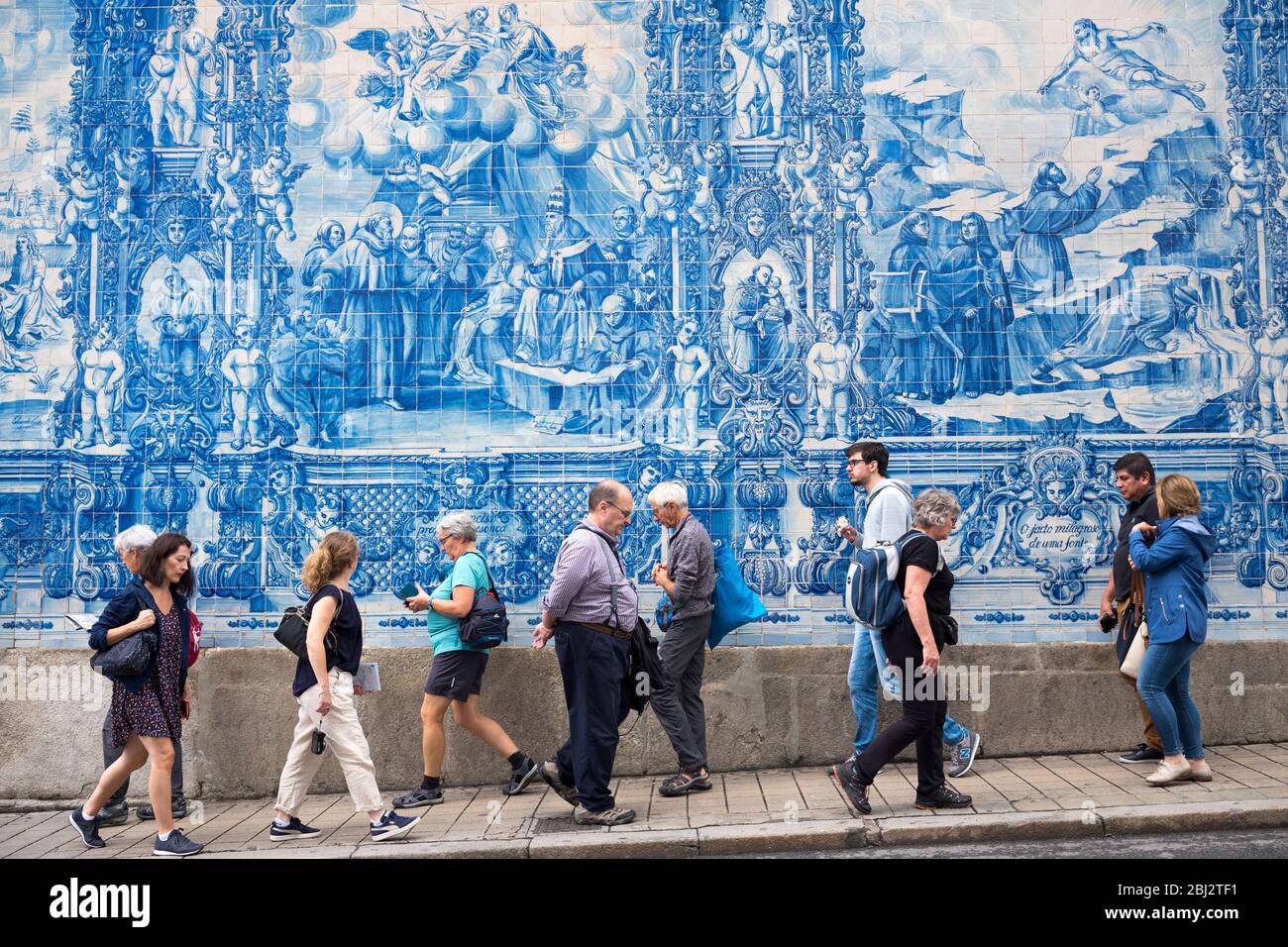 People passing azulejos Portuguese blue and white wall tiles of Capela das Almas de Santa Catarina  - St Catherine's Chapel in Porto, Portugal Stock Photo