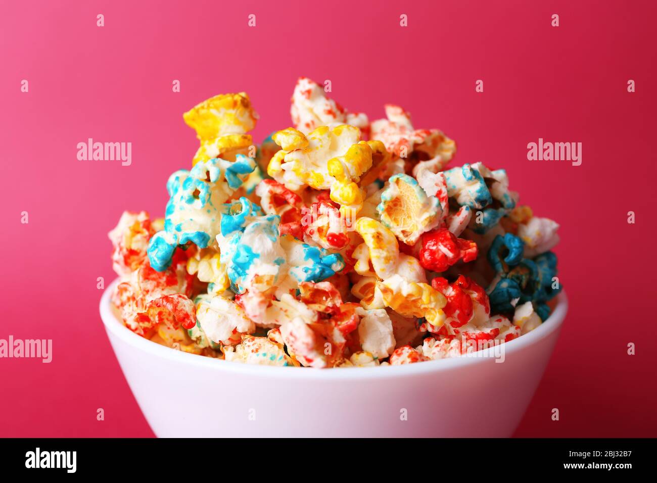 Sweet colourful popcorn on pink background Stock Photo