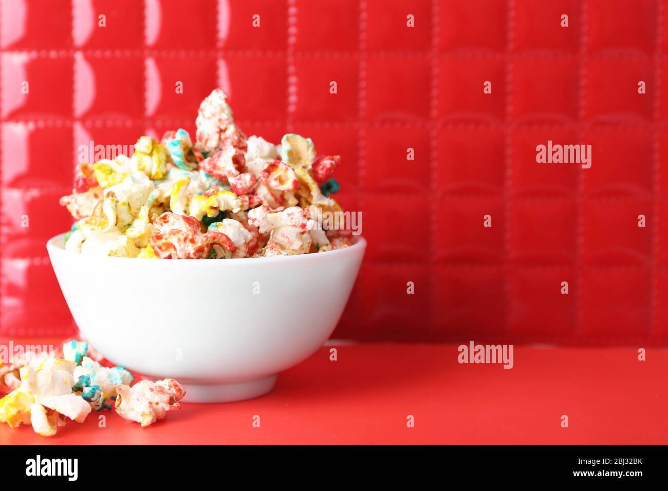 Sweet colourful popcorn on red background Stock Photo