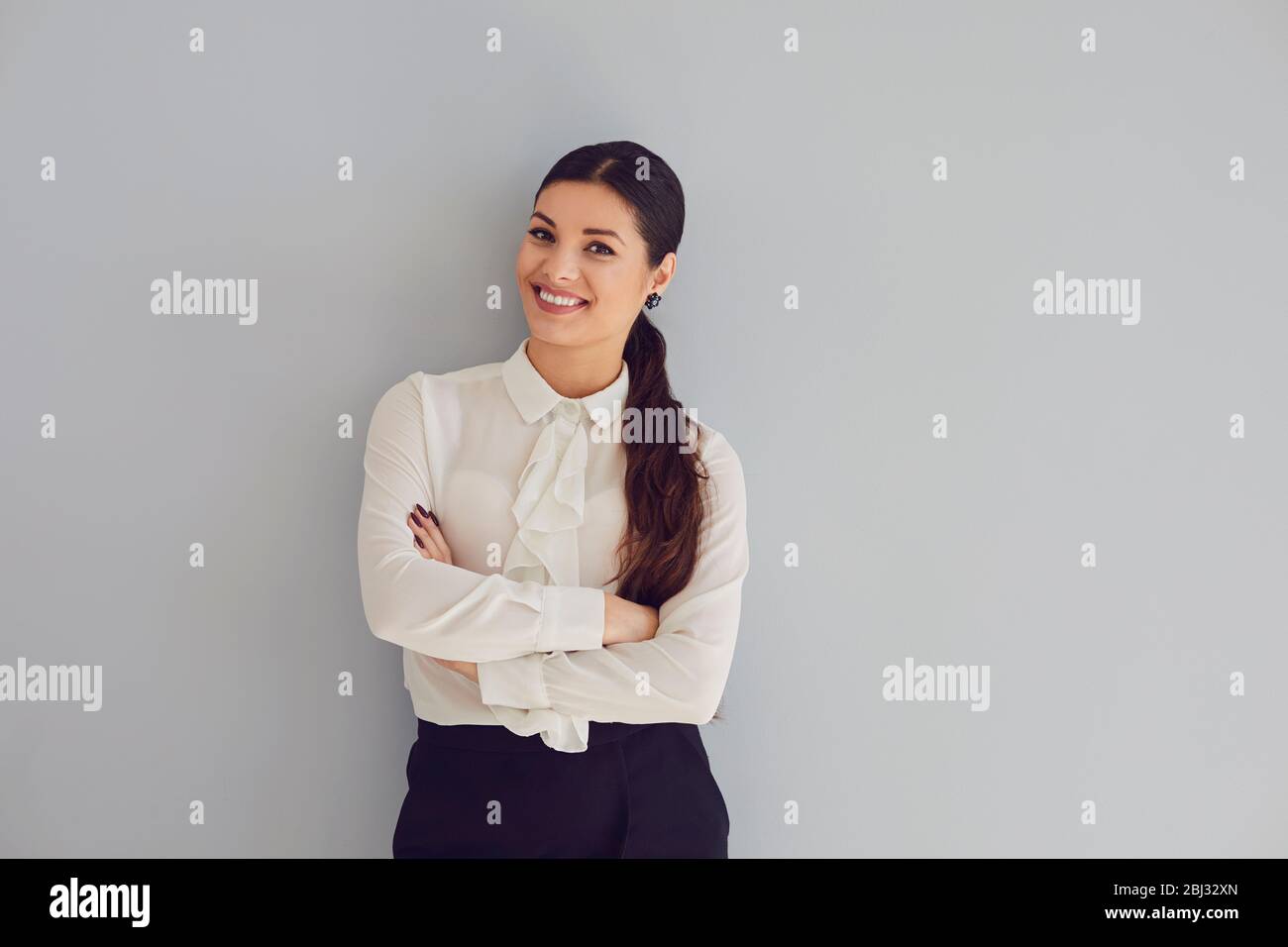 Young woman in white shirt smiling laughs joyful happy positive on a gray background. Stock Photo