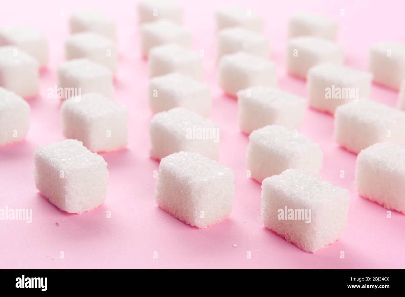 Cubes of sugar on bright pink background Stock Photo - Alamy