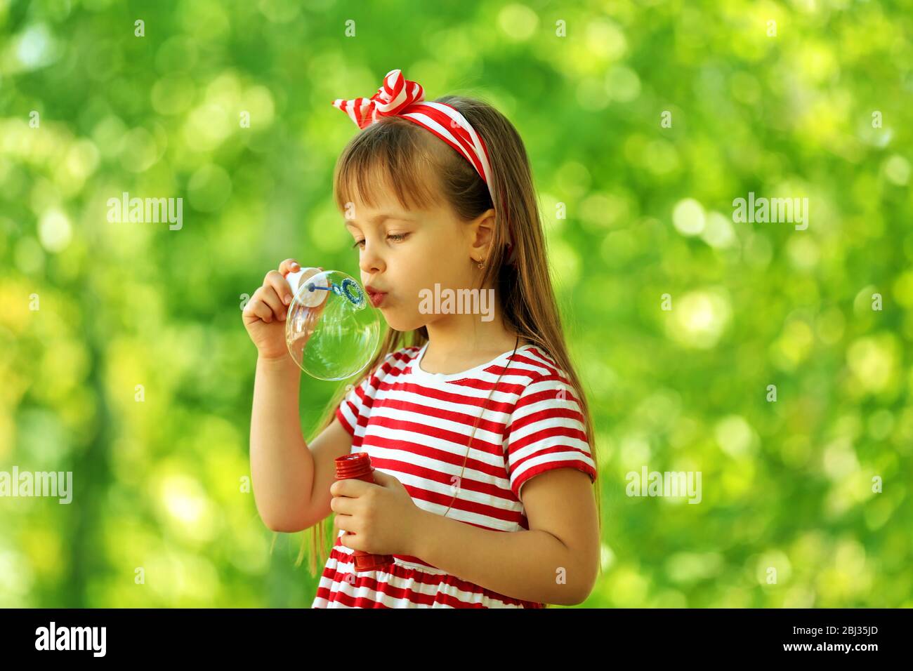 Little girl playing with bubbles in the park Stock Photo - Alamy
