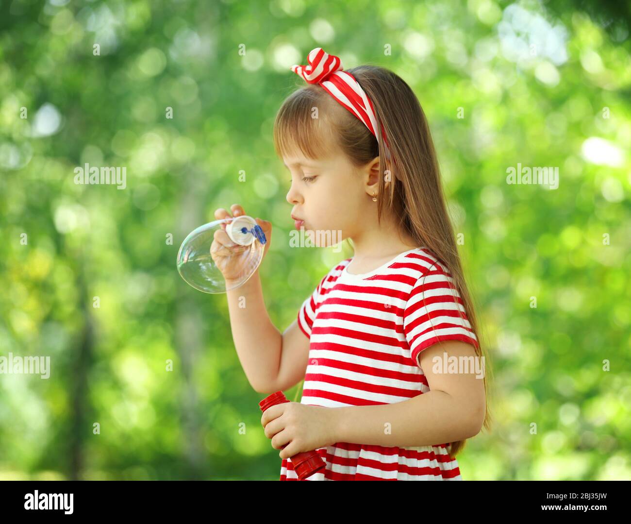 Little girl playing with bubbles in the park Stock Photo - Alamy