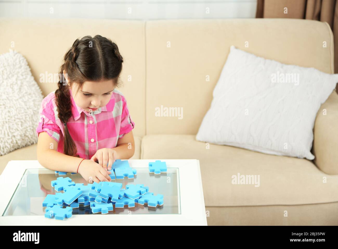 Cute little girl playing with puzzles on home interior background Stock ...