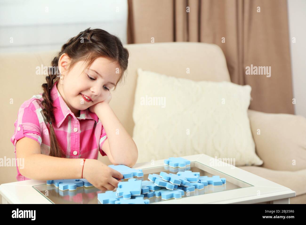 Cute little girl playing with puzzles on home interior background Stock ...