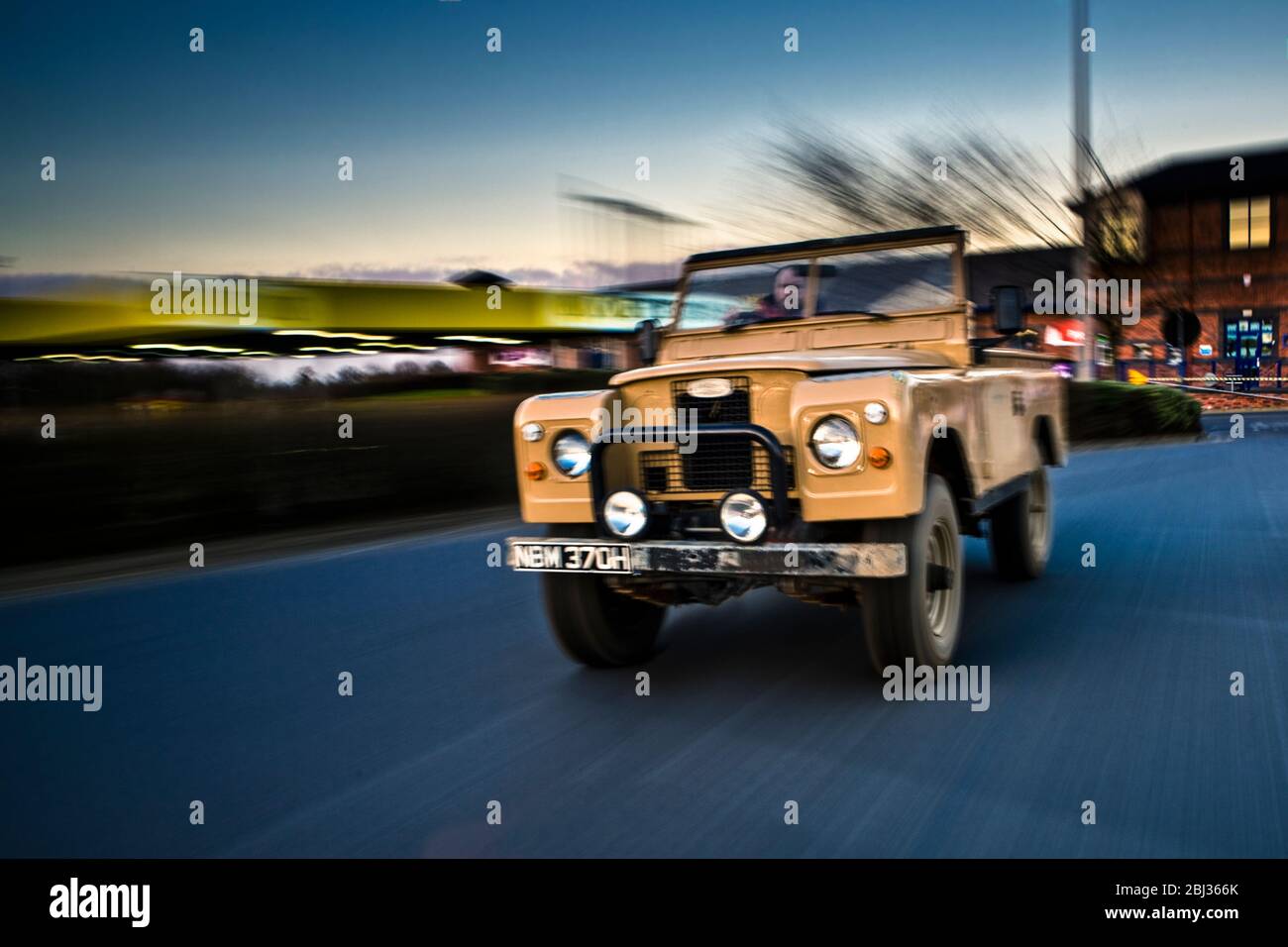 An old Series Land Rover drives away from a superstore. Stock Photo