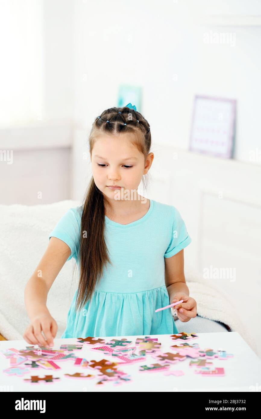 Cute little girl playing with puzzles on home interior background Stock ...
