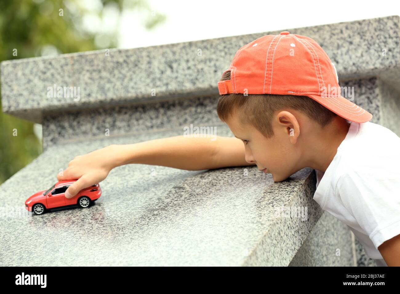 Little boy playing with toy car outside Stock Photo - Alamy