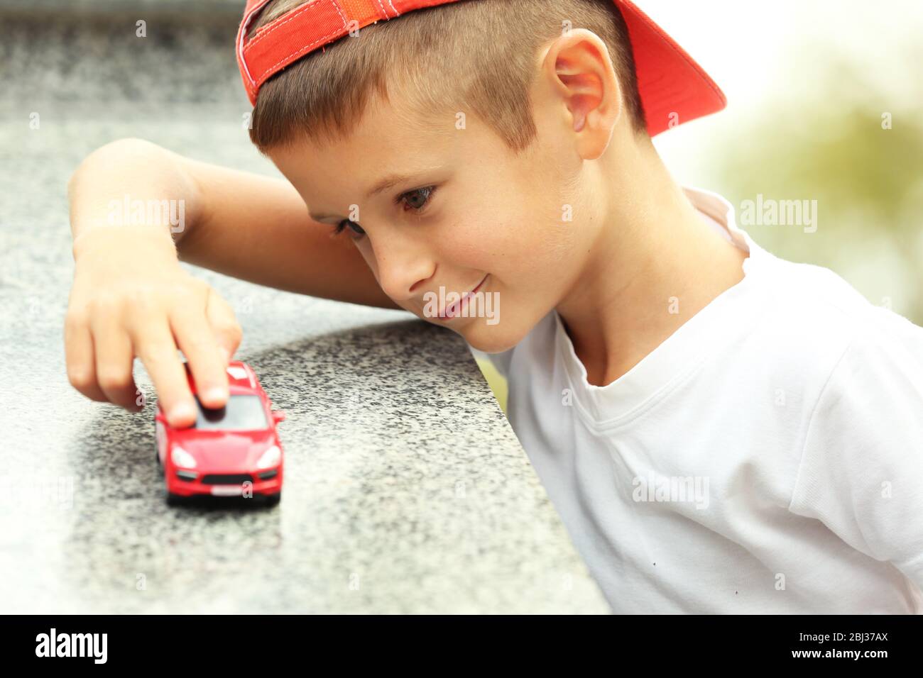 Little boy playing with toy car outside Stock Photo - Alamy