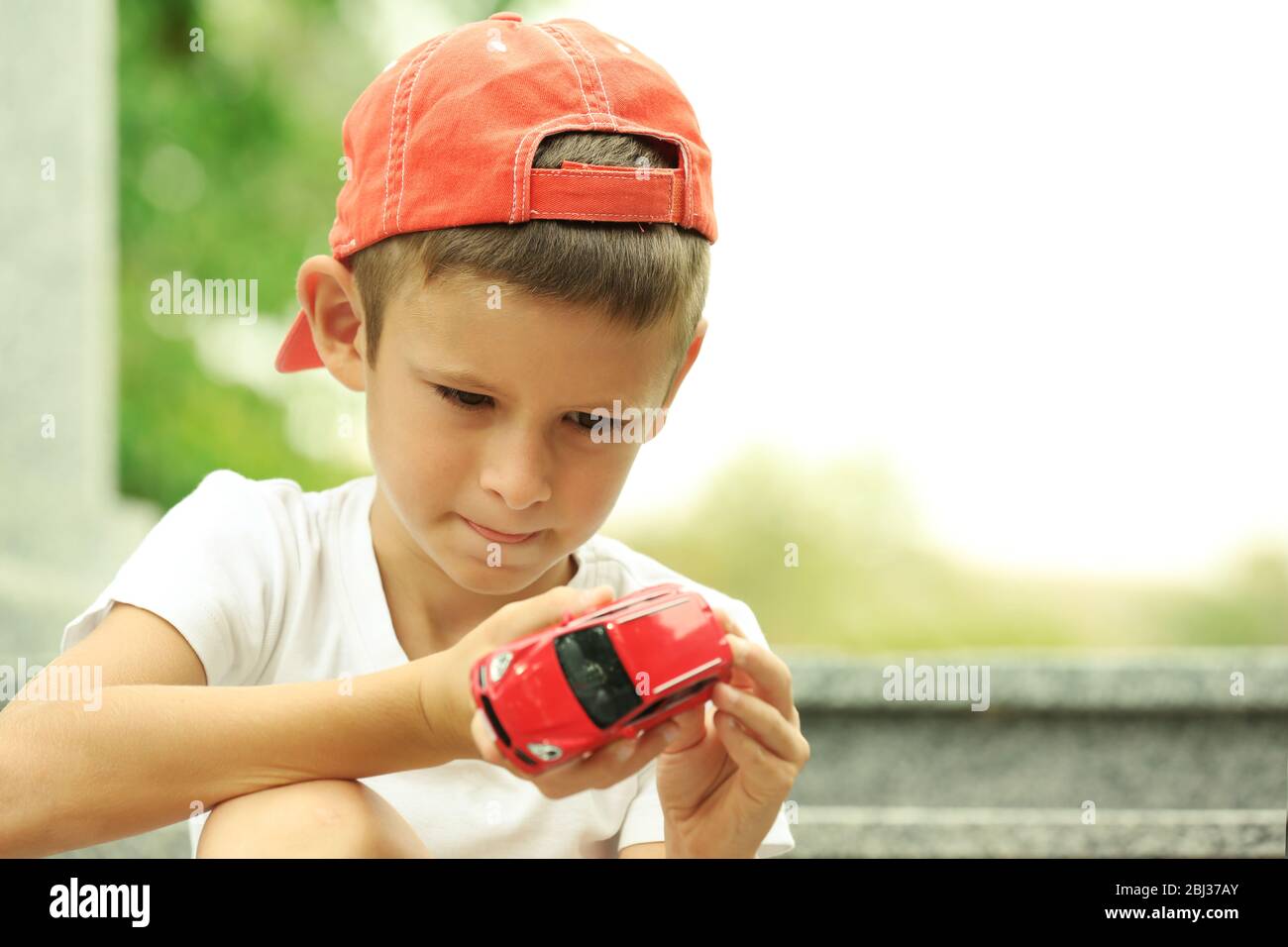 Little boy playing with toy car outside Stock Photo - Alamy