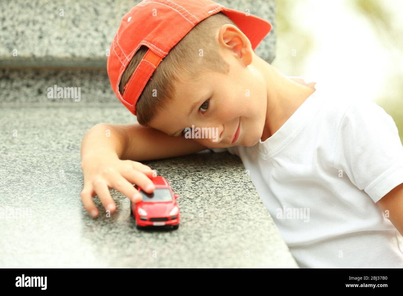 Little boy playing with toy car outside Stock Photo - Alamy