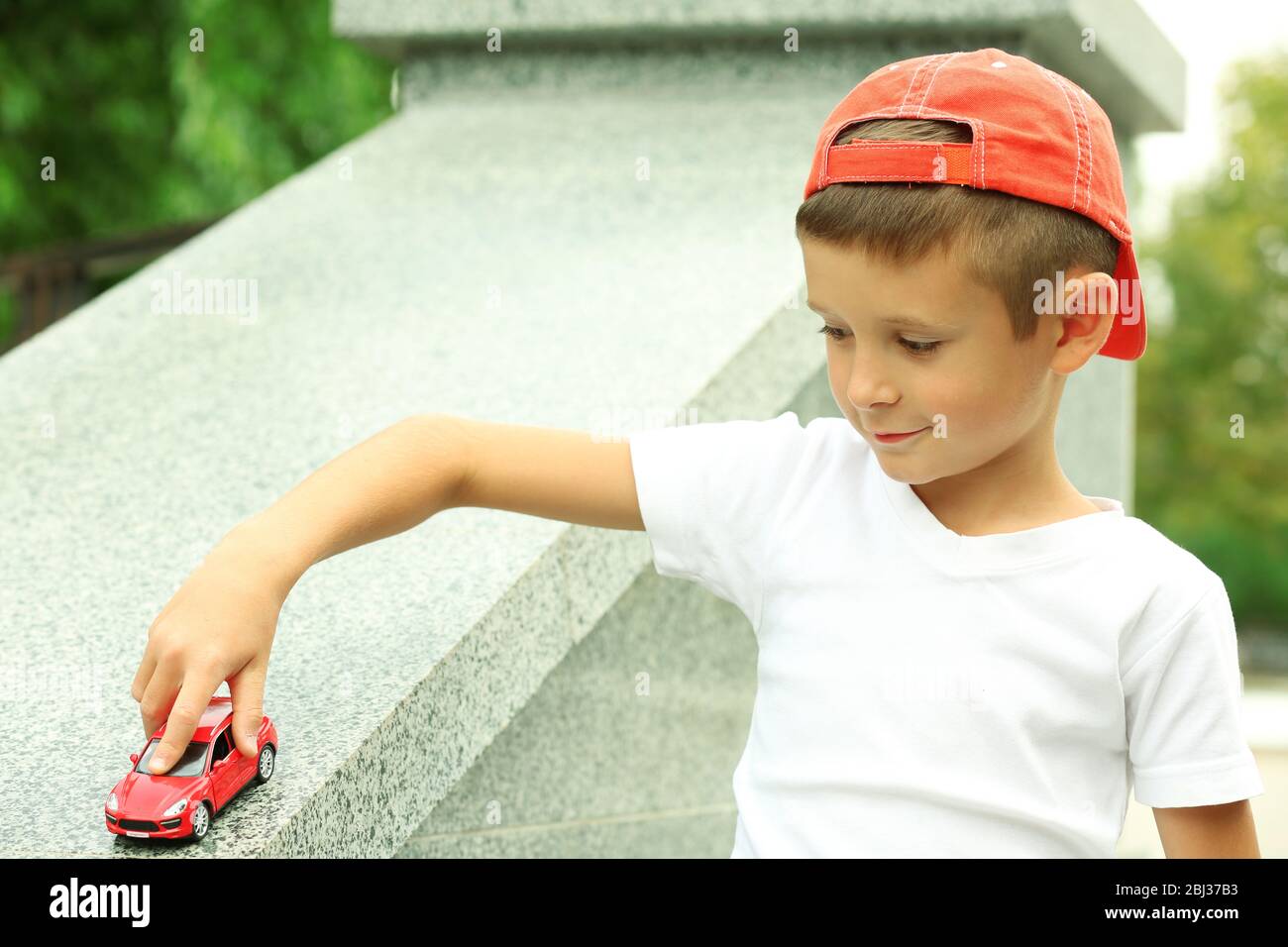 Little boy playing with toy car outside Stock Photo - Alamy