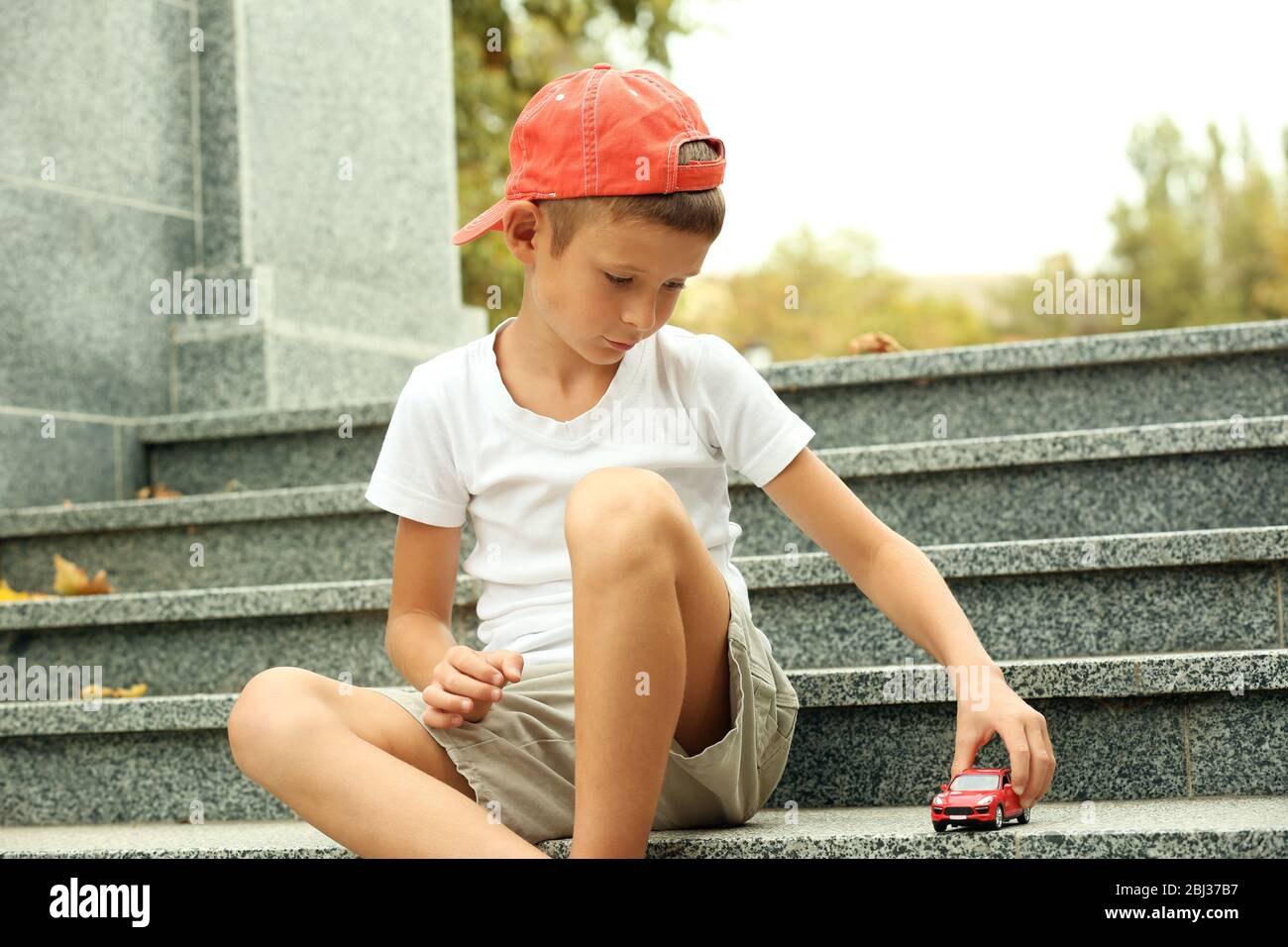 Little boy playing with toy car outside Stock Photo - Alamy