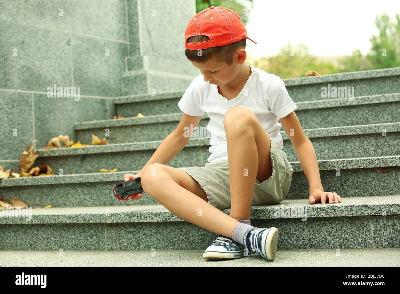 Little boy playing with toy car outside Stock Photo - Alamy