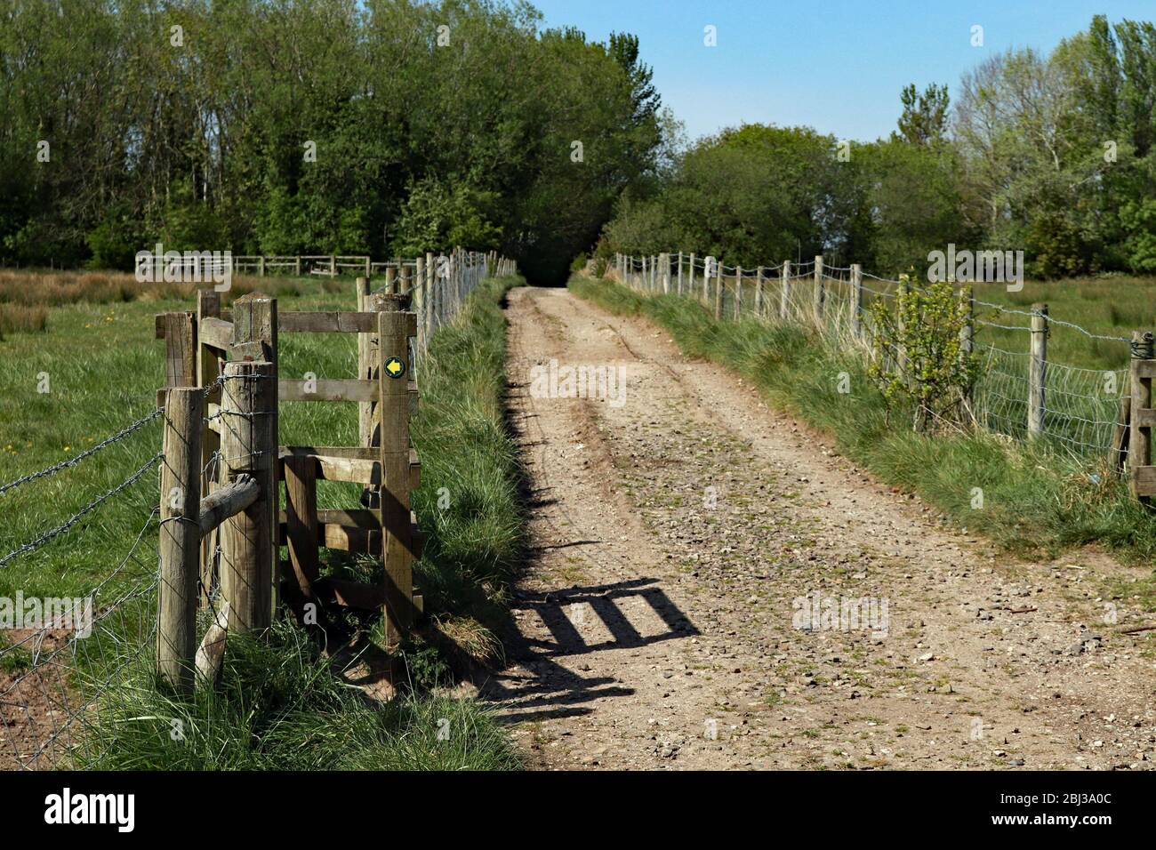 Foot path, with a style in a boundary fence, running from Blythe Lane towards the Platts Lane Lake near Burscough in West Lancashire on a sunny day. Stock Photo
