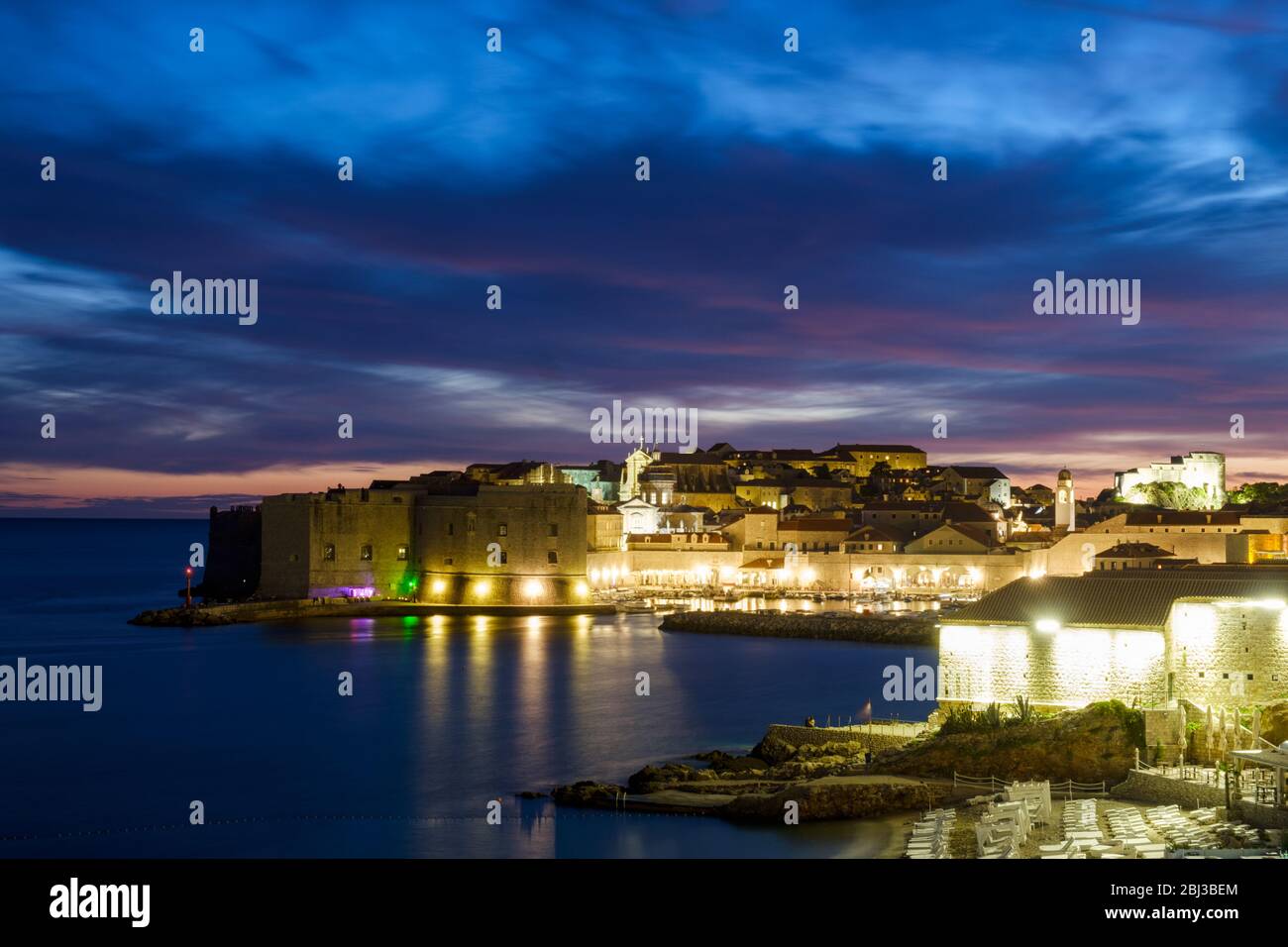 A shot of Dubrovnik, Croatia, taken at dusk and shot across the Adriatic sea towards the area known as Old Town and the Old Town port Stock Photo