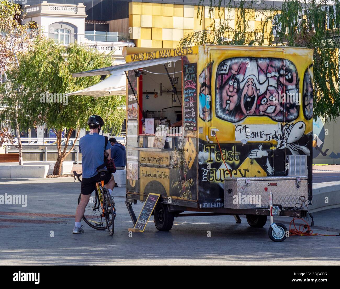 Male cyclist buying Indian take away food from a food van in Yagan Square Perth Western Australia. Stock Photo